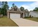 Low angle of a single-story home with stone accents and a two-car garage on a well-manicured lawn at 5081 Pioneer Dr, Sanford, NC 27330