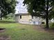 Spacious backyard with a view of home's exterior, green grass, and mature trees at 510 North St, Graham, NC 27253