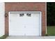 Close up of a one car garage door with brick accents and a carriage light at 5200 Fieldwood Ct, Raleigh, NC 27616