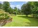 Expansive backyard featuring a lush green lawn, mature trees, and a stone retaining wall at 559 Blue Pond Rd, Clayton, NC 27520