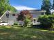 View of the rear exterior featuring an attached garage, leafy trees, and a well-maintained lawn at 5760 Hesters Store Rd, Hurdle Mills, NC 27541