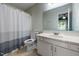 Bathroom features white vanity and shower/tub with neutral-toned curtain and large mirror at 6021 Dixon Dr, Raleigh, NC 27609