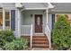 Close up view of the blue home's front door with brick steps and manicured landscaping at 8 Great Oak Ct, Durham, NC 27713
