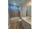 Modern bathroom with tiled shower-tub, granite countertop vanity, and hardwood floors at 85 Bald Cypress Ln, Youngsville, NC 27596