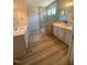 Modern bathroom featuring dual vanities, a tiled shower, and wood-look flooring at 85 Bald Cypress Ln, Youngsville, NC 27596
