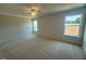 Spacious bedroom with neutral carpet, a ceiling fan, and two windows overlooking the yard at 85 Bald Cypress Ln, Youngsville, NC 27596