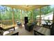 Relaxing screened-in porch features comfortable wicker furniture, a fire pit table, and wooded views at 966 Airedale Trl, Garner, NC 27529