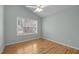 Cozy bedroom featuring sleek hardwood floors, a ceiling fan, and a large window at 100 W Acres Cres, Cary, NC 27519