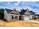 View of home shows neutral vinyl siding, brick accents, a two car garage, and landscaped yard at 1079 Fairhaven Dr # 50, Mebane, NC 27302