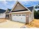 View of home shows neutral vinyl siding, brick accents, a two car garage, and landscaped yard at 1079 Fairhaven Dr # 50, Mebane, NC 27302