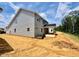 Rear view of a new home with gray siding, showcasing large windows and a covered patio area surrounded by greenery at 1079 Fairhaven Dr # 50, Mebane, NC 27302