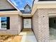 A bright, inviting doorway of a new home featuring a white door with glass details and brick accents at 1079 Fairhaven Dr # 50, Mebane, NC 27302