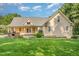 Beautiful backyard showcasing a lush lawn, mature trees, stone fireplace, and covered porch at 1096 Silverleaf Dr, Youngsville, NC 27596