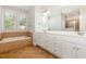 Bright bathroom featuring a soaking tub, double vanity, and neutral tile flooring at 1096 Silverleaf Dr, Youngsville, NC 27596