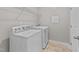 Well-lit laundry room with white washer and dryer, tiled floors, and shelving at 119 Yadkin St, Clayton, NC 27520