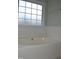 Garden tub in bathroom with tile accents and a frosted window at 136 Wedgewood Ct, Sanford, NC 27332