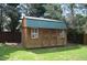 Backyard view of wooden storage shed with green metal roof and double doors at 136 Wedgewood Ct, Sanford, NC 27332