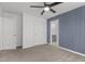 Carpeted bedroom featuring a paneled accent wall, ceiling fan, and multiple doorways at 1414 Arena Ln, Fuquay Varina, NC 27526