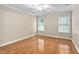 A bedroom featuring hardwood floors, a ceiling fan and two windows for natural light at 2 Lake Village Dr, Durham, NC 27713