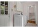 Functional laundry room with white appliances, storage cabinets, and access to the exterior and stairs at 200 Frenchmans Bluff Dr, Cary, NC 27513