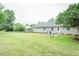 Wide shot of a large backyard with green grass, a play set, patio and home's exterior at 2120 Northcrest Dr, Elon, NC 27244