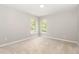 Bedroom with neutral walls, soft carpeting, and two large windows offering serene views at 2409 Valley Haven Dr, Raleigh, NC 27603