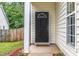 Front door with a 'Hello' welcome mat, surrounded by greenery and a glimpse of a white picket fence at 2409 Valley Haven Dr, Raleigh, NC 27603