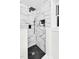 Modern shower featuring marble-patterned tiles, a sleek black shower head, and black hexagon-tiled flooring at 301 Lord Berkley Rd, Raleigh, NC 27610