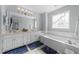 Bright bathroom with a double sink vanity, a large mirror, and a separate soaking tub with tile surround at 304 Indigo Pl, Garner, NC 27529