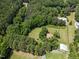 Aerial view of home surrounded by mature trees, a mix of open lawn space and forest, and a barn on the property at 3044 Rock Springs Church Rd, Creedmoor, NC 27522