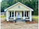 Inviting home exterior featuring a cozy front porch with black railings and manicured landscaping at 307 N Church St, Kenly, NC 27542
