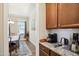 Kitchenette featuring brown cabinets, granite countertops, a coffeemaker and a view into the dining room at 33 Village Walk Dr, Chapel Hill, NC 27517