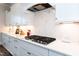 Close up of a modern kitchen area featuring a gas cooktop, designer backsplash, and sleek white countertops at 4104 Green Chase Way, Apex, NC 27539