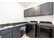 Modern laundry room with granite countertops, sink, cabinets, and front loading black washer and dryer at 4104 Green Chase Way, Apex, NC 27539