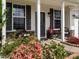 Inviting front porch with stone accents and outdoor seating surrounded by colorful flowers at 4179 Dunkirk Dr, Burlington, NC 27215