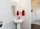 Stylish half bathroom features a pedestal sink, decorative mirror, and red accents at 4179 Dunkirk Dr, Burlington, NC 27215