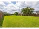 Large backyard with a healthy lawn, wooden fence, and a variety of mature trees at 418 Lodestone Dr, Durham, NC 27703