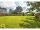 Well-kept backyard with a vast green lawn, a sturdy wooden fence, and surrounding trees at 418 Lodestone Dr, Durham, NC 27703