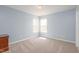 Cozy bedroom featuring neutral carpet, natural light from two windows, and a light blue painted wall at 418 Lodestone Dr, Durham, NC 27703