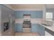 Modern kitchen featuring granite countertops, a stainless steel refrigerator, and updated blue cabinets at 418 Lodestone Dr, Durham, NC 27703
