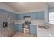 Well-lit kitchen featuring stainless steel appliances, updated countertops, and stylish blue cabinets at 418 Lodestone Dr, Durham, NC 27703