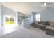 Open-concept living room features a gray sofa, modern ceiling fan, and view into the updated kitchen at 418 Lodestone Dr, Durham, NC 27703