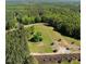 Areal shot featuring a lush property with trees, an open area, winding road, and a beautiful lake in the distance at 429 Shinleaf Pond Trl, Raleigh, NC 27614