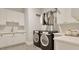 Modern laundry room with white cabinets, sleek black washer and dryer, and ample counter space at 429 Shinleaf Pond Trl, Raleigh, NC 27614