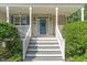 Inviting front porch with white railings, stairs, blue door with wreath, and manicured landscaping at 457 Poplar Forest Ln, Pittsboro, NC 27312