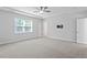 Spacious main bedroom features plush carpeting, a ceiling fan, and ample natural light at 4940 Enlightenment Rd, Raleigh, NC 27616