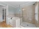 Bathroom with a tub and walk-in shower featuring tiled walls and a frameless glass door at 541 Mallie Pearce Rd, Zebulon, NC 27597