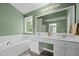 Bright bathroom with double vanity, large mirror, tub, and decorative light fixture at 603 Everglades Dr, Mebane, NC 27302
