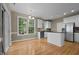 Bright kitchen with hardwood flooring, white cabinets, stainless appliances, and large windows at 603 Everglades Dr, Mebane, NC 27302