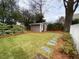 View of backyard featuring well-maintained lawn, mature trees and shrubs, and a storage shed at 627 New Road, Raleigh, NC 27608